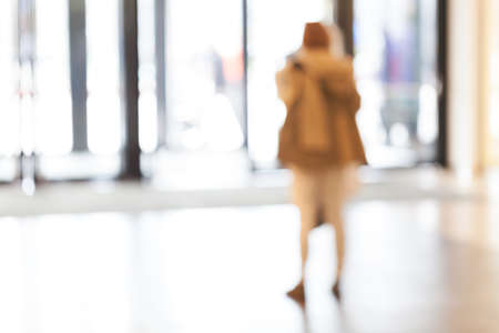 silhouettes of people as they move through the mal with light backgroundl, for the bluured backgroundの写真素材