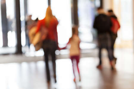 silhouettes of people as they move through the mal with light backgroundl, for the bluured backgroundの写真素材