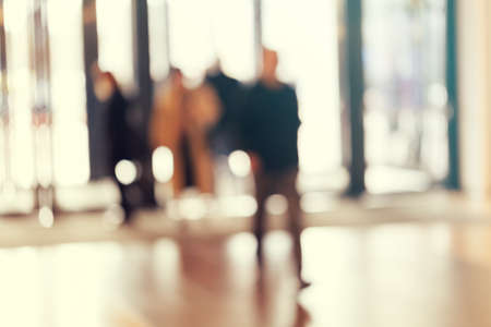 silhouettes of people as they move through the mal with light backgroundl, for the bluured backgroundの写真素材
