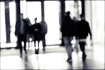 silhouettes of people as they move through the mal with light backgroundl, for the bluured...