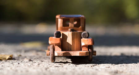 old retro wooden toy car on the road in autumn forestの写真素材