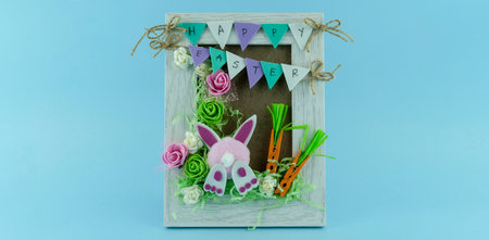 Handmade Creative Easter frame with flowers and cute bunny on blue backgroundの写真素材