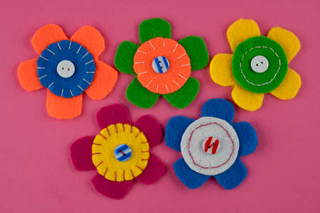 Handmade cute colorful flowers with buttons on pink backgroundの写真素材