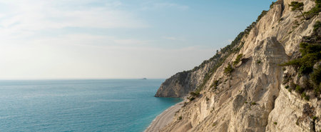 Beautiful wild Mediterranean pebble beach under a large massive cliffの写真素材