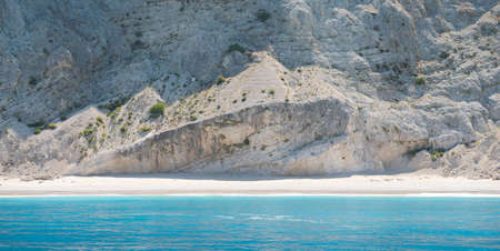 Beautiful wild Mediterranean pebble beach under a large massive rockの写真素材