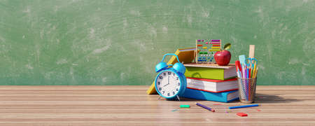 School supplies on wooden table with blackboard in the background. Books and colorful pencils with...