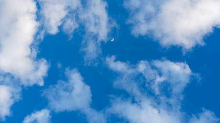 Beautiful vivid blue sky with white clouds and moon in backgroundの写真素材