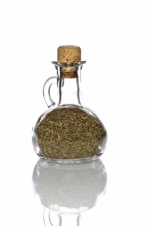 Thyme in a glass bottle with a cork and isolated with reflection on whiteの写真素材