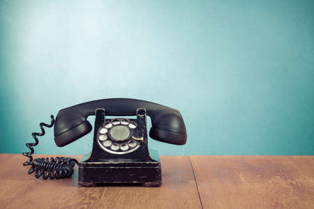 Retro telephone on table in front mint green background Retro telephone on table in front mint green background