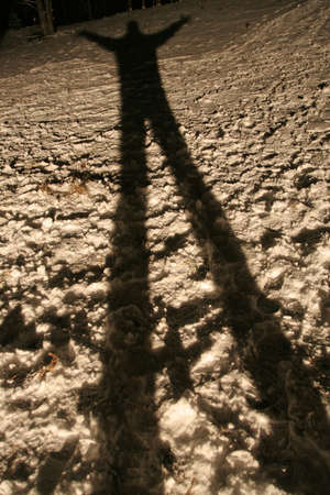 Long and spooky looking shadow of a man on the snowの写真素材