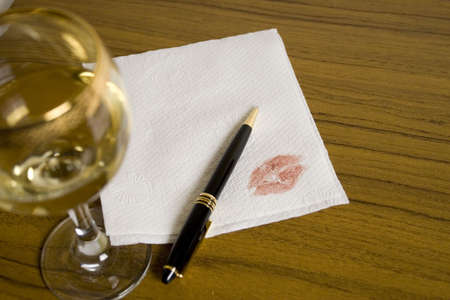 Blank napkin, pen and a glass of whine on the foregroundの写真素材