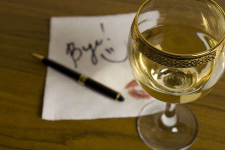 Glass of wine and out of focus word Bye! on the cocktail napkin. Date didn't go as planned