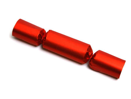Closeup of a single red Christmas English party crackers isolated over white. Lost of space for your text or design. Party Crackers are an old English party favor idea and tradition. They are festively wrapped cardboard cylinders that can be filled with all manner of treasures and trinkets and tied off at the ends. A cracker "snap" is inserted which, when pulled from both ends, pops loudly.の写真素材