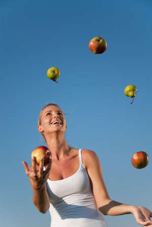 young woman juggling with healthy food outdoorsの写真素材