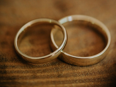 Gold pair of rings on a wooden tableの写真素材