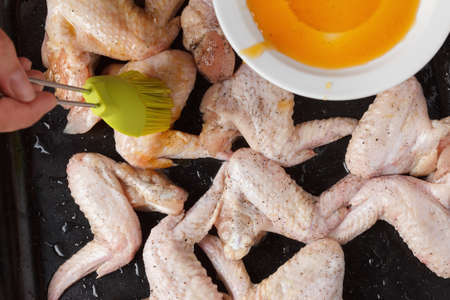 Prepare raw chicken wings on a baking sheet. Pastry brush lubricates. Before fryingの写真素材