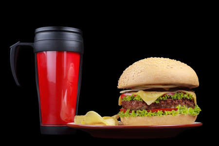 Tasty burger with fresh beef, vegetables and spices on a plate, potato chips. Isolated black background, studio shot. The drink, cola, lemonade.の写真素材