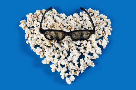 Stereo glasses and Popcorn Heart , Heart shaped frame made of popcorn over the blue backgroundの写真素材