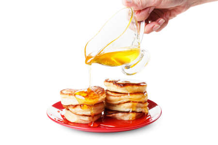 Chef pours sweet syrup, or  honey, on flapjacks. White backgroundの写真素材