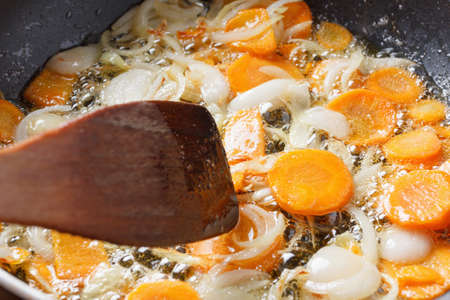 Onions and carrots in the pan. Bubbles of sunflower oil in a large frying panの写真素材
