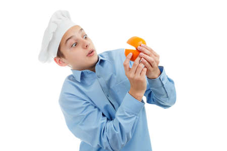 Portrait of teen Cook holding orange. Isolated on white background.の写真素材