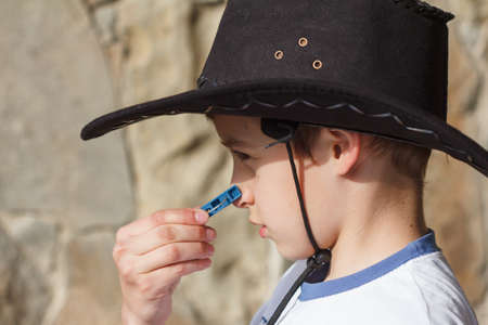 boy wearing a cowboy hat looks ridiculous with clothespin closeupの写真素材