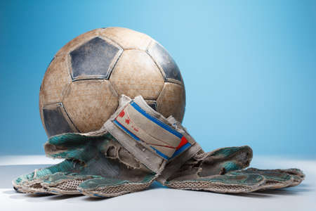 Old dirty Soccer goalkeeper's gloves and the ball, with blue color in the backgroundの写真素材