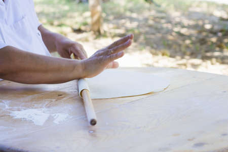 Chef rolls dough for tortillas on the tableの写真素材