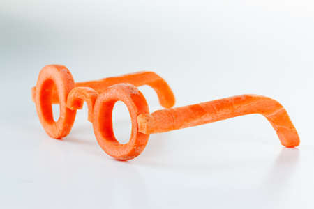 Concept glasses of carrot carotene benefits for vision. Proper nutrition improves vision. On white bsckgroundの写真素材