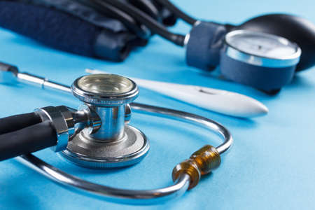 Medical devices stethoscope, tonometer, and thermometer on blue backgroundの写真素材