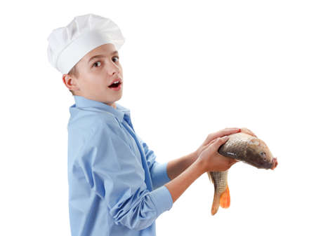 Young caucasian chef holding a fish carp. Cooking wholesome food. Isolated on white backgroundの写真素材