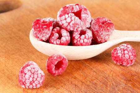 Frozen raspberries on the cutting board closeup with snow and ice