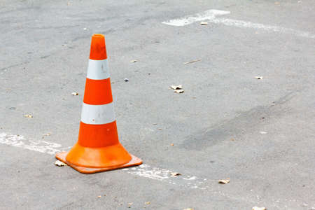 Road cone on the asphalt. Fallen leaves.の写真素材