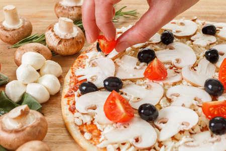 Food ingredients for pizza on table close up. Cooking homemade pizza with fresh vegetables and olivesの写真素材