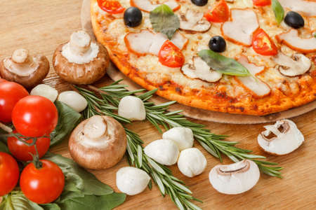 Pizza with mushrooms, olives and tomatoes. Basil, rosemary and fresh vegetables. Freshly homemadeの写真素材