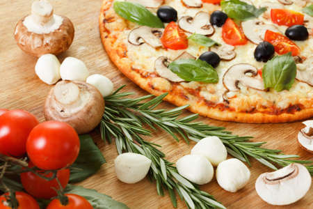 Pizza with mushrooms, olives and tomatoes. Basil, rosemary and fresh vegetables. Freshly homemadeの写真素材
