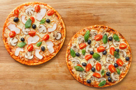 Top view two Pizza with mushrooms, olives and tomatoes. Basil, rosemary and fresh vegetables. Freshly homemadeの写真素材