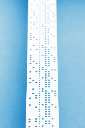 Closeup of perforated punched tape, obsolete data storage, on blue backgroundの写真素材