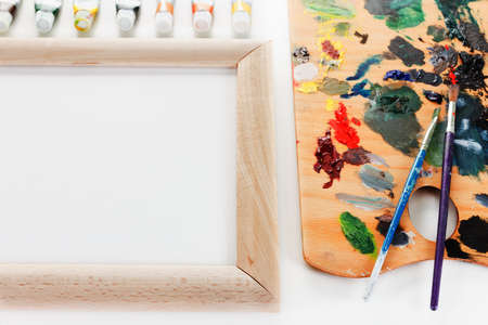 Art palette with paint, border and a brush on white backgroundの写真素材