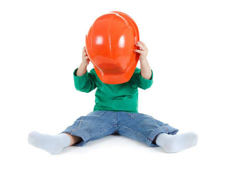 Little child plays with orange construction protective helmet  on white background. Profession future builder.の写真素材