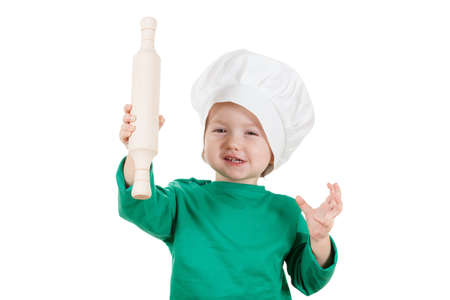 Smiling little cook boy kneading the dough for the cookies, isolated on white background.  Half-length portrait of the table in studioの写真素材