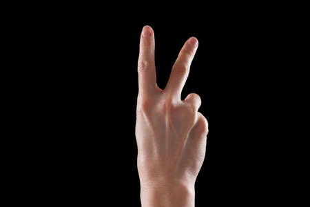 Gesture, a beautiful young woman's hand indicates the direction or making gestures on touch devices. Isolated on black backgroundの写真素材