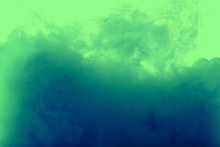Color drop in water, photographed in motion. Ink swirling in water. Cloud of ink in water isolated on white background. Colorful ink in water, ink drop.の写真素材
