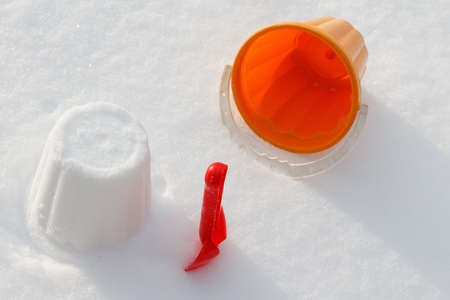 Overhead view on colorful toys, bucket and shovel which are filled up with snow, covered snow,  on...