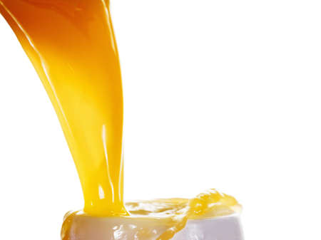 pouring a glass of orange juice creating splash isolated on white backgroundの写真素材