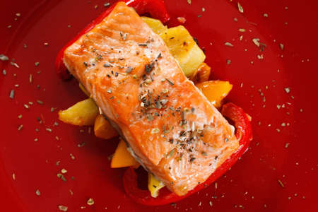Baked prepared salmon fillet with vegetables, spices and arugula on a plate closeupの写真素材