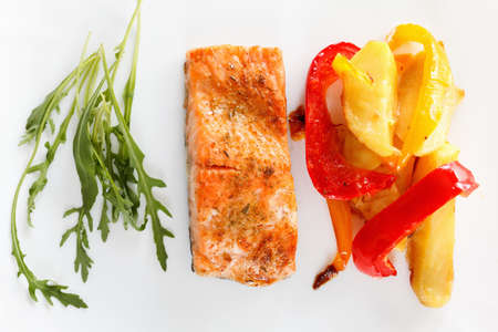 Baked prepared salmon fillet with vegetables, spices and arugula on a plate closeupの写真素材
