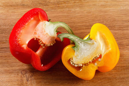 fresh red and yellow bell pepper, cut one on wooden background closeup