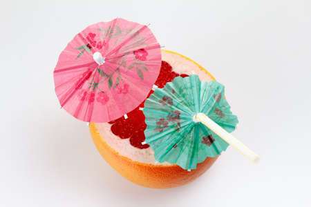 Cut grapefruit cocktail with umbrella, on white  backgroundの写真素材