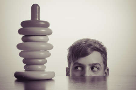 Caucasian boy playing with a toy pyramid. Old advertising concept, development of teenagers. Photo in vintage style of old picturesの写真素材